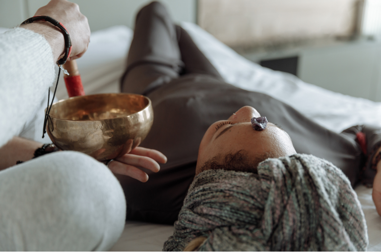 A women receiving a private sound therapy session. She has an amethyst crystal on the space between her eyebrows.